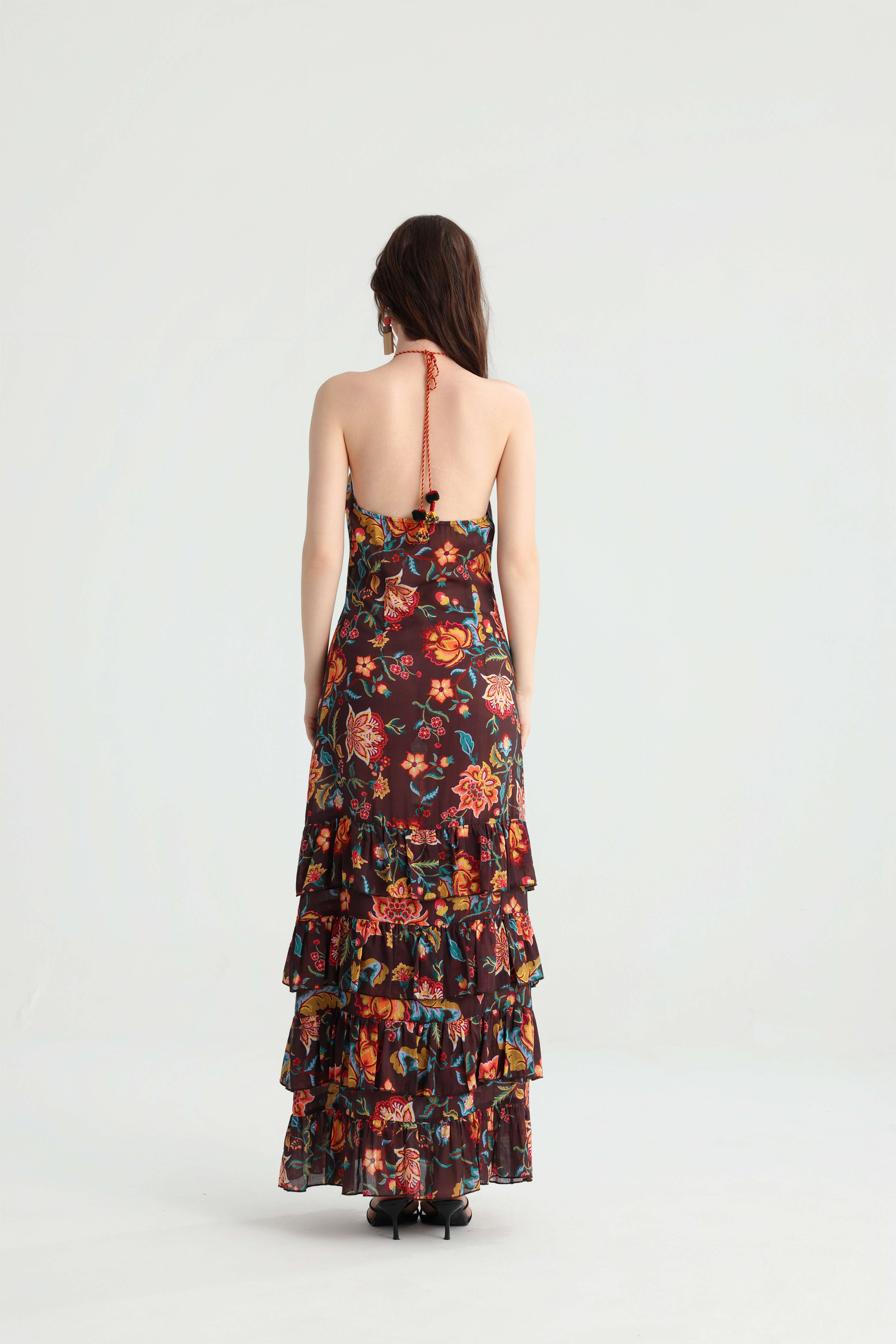 Back view of the floral maxi dress showing the open back, halter tie and tiered ruffles