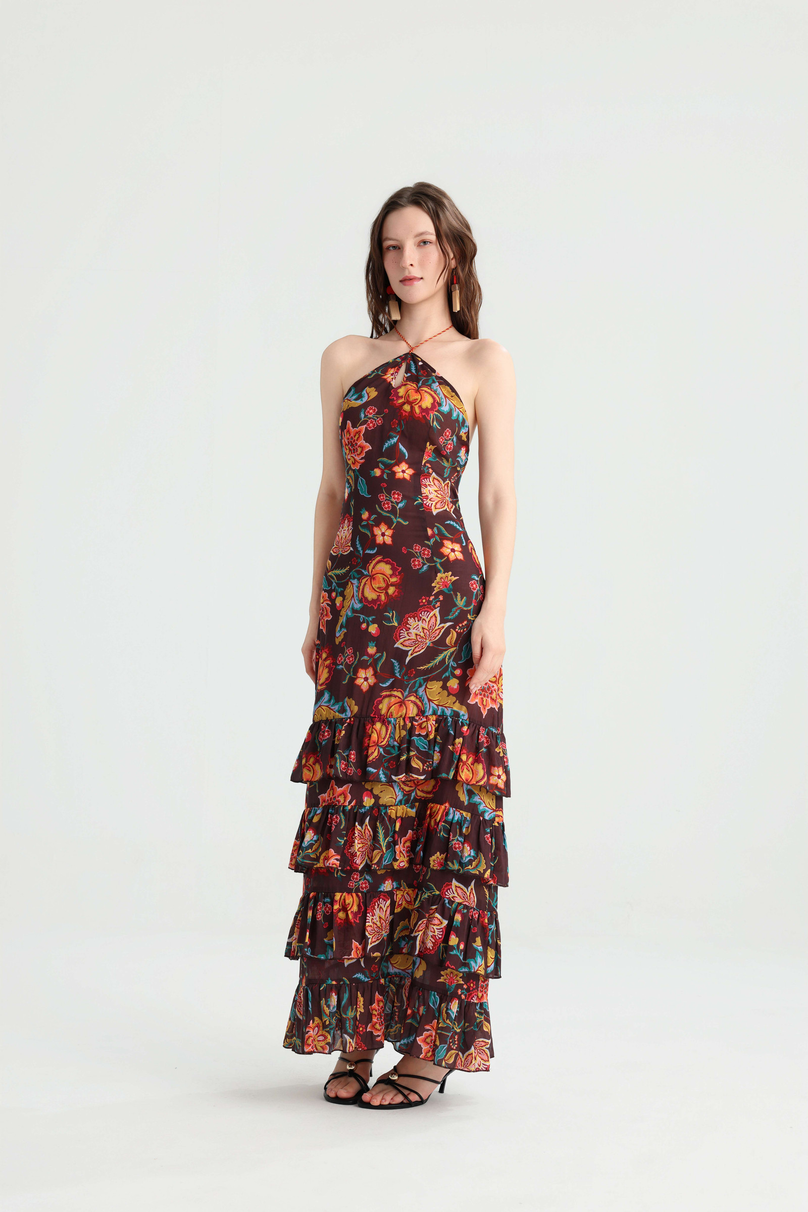 Front view of a dark brown floral halter maxi dress with a tiered ruffle skirt