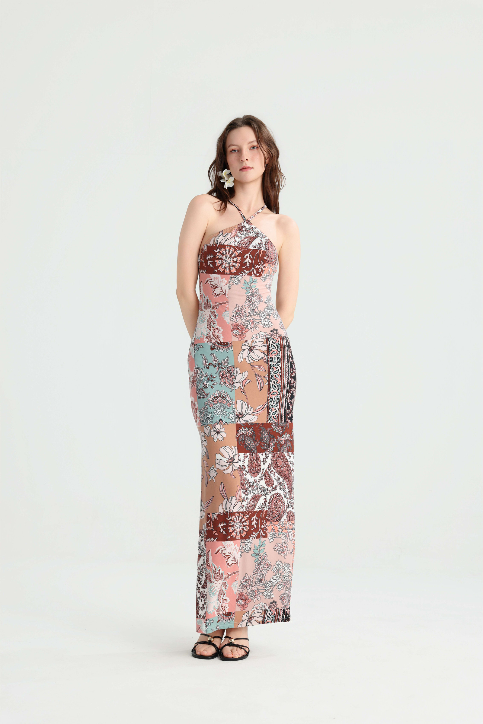 Model posing with her hands behind her back in the fitted patchwork halter maxi dress