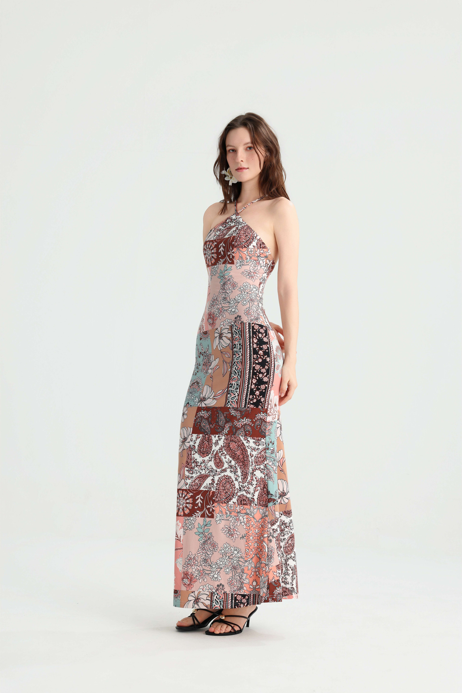 Side-angled view of the patchwork halter maxi dress showing its fitted silhouette and floral panels